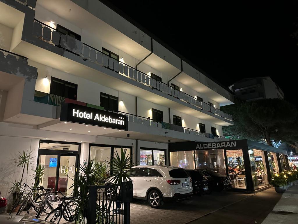 une voiture blanche garée devant un hôtel la nuit dans l'établissement Hotel ALDEBARAN, à Lido di Jesolo