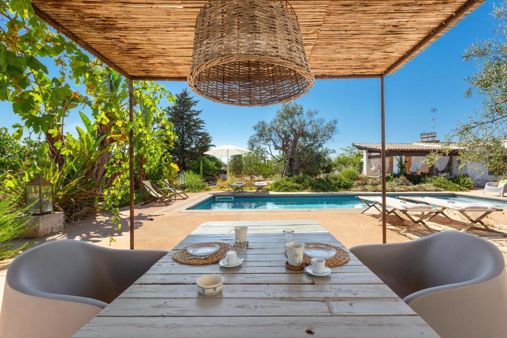 - une table en bois avec des chaises en face de la piscine dans l'établissement Le Cerase, à Salve 50 autres photos