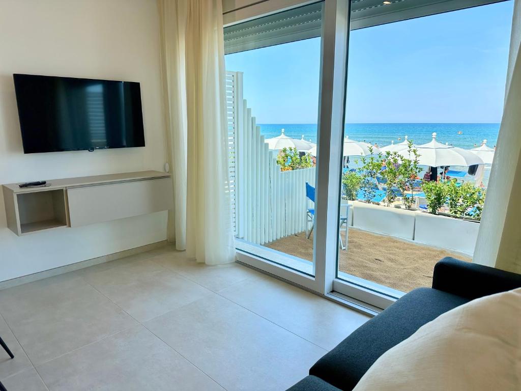 - un salon avec une télévision et une vue sur l'océan dans l'établissement Florida Apartments, à San Vincenzo
