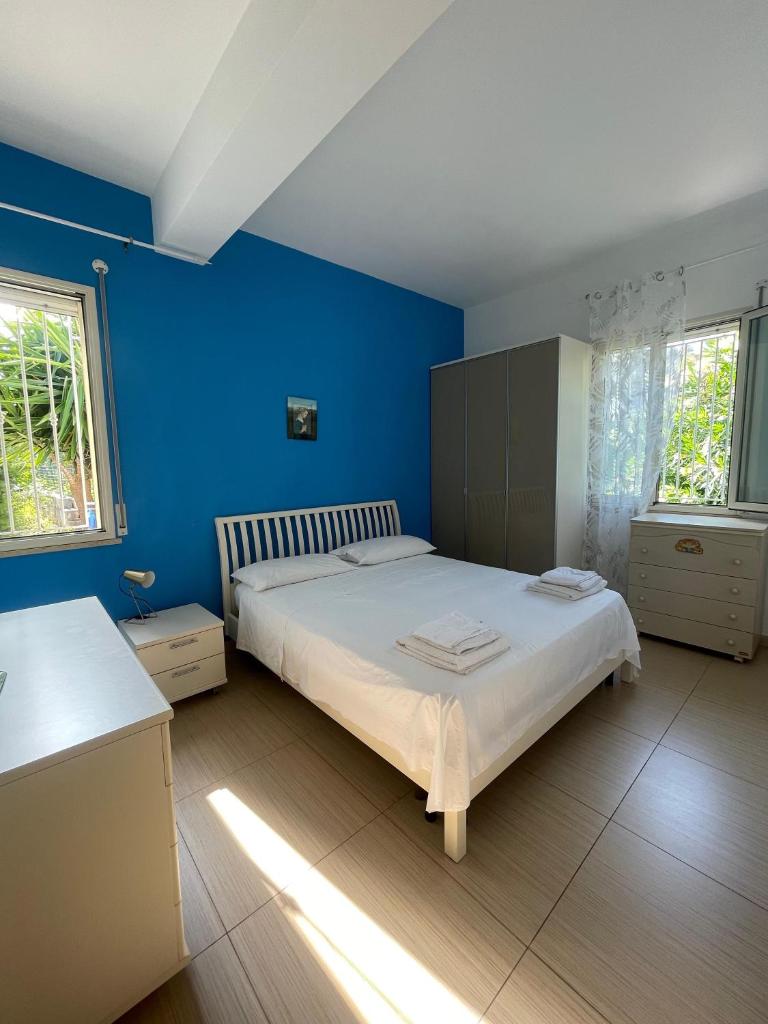 une chambre avec un grand lit aux murs bleus dans l'établissement Villa Spiaggia Plaja, à Castellammare del Golfo
