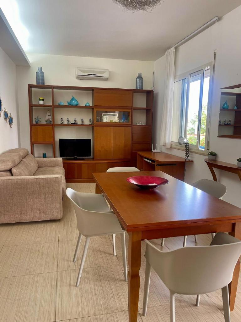 un salon avec une table et des chaises en bois dans l'établissement Villa Spiaggia Plaja, à Castellammare del Golfo