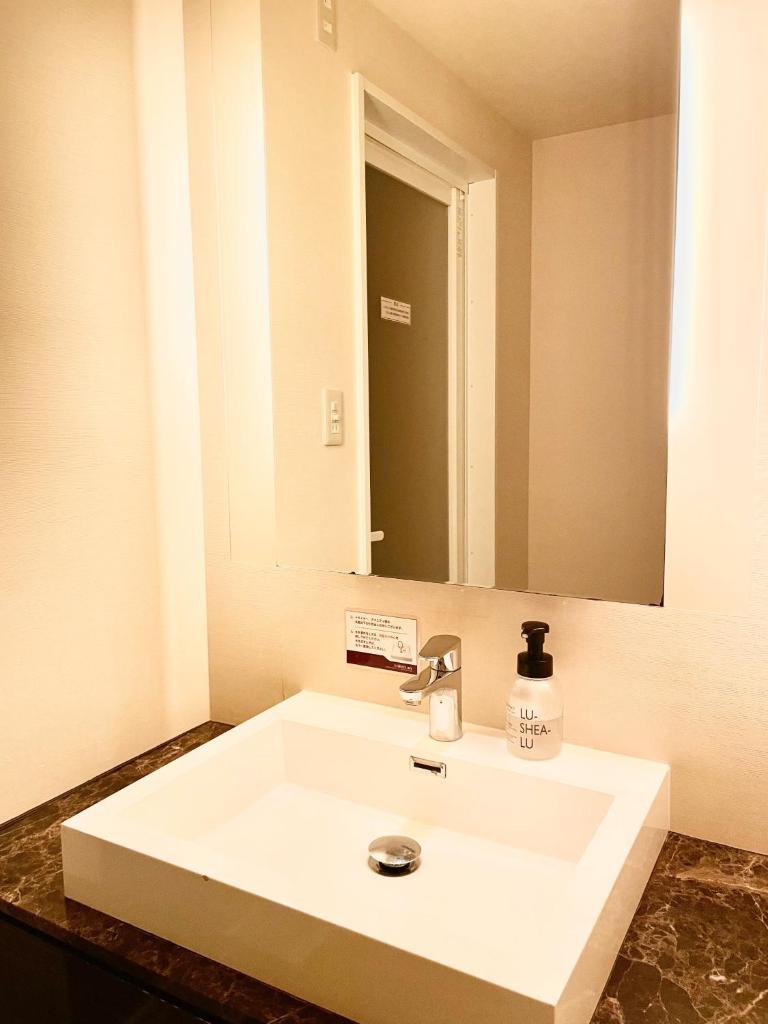 un lavabo blanc dans une salle de bain avec un miroir dans l'établissement Hotel BIX チェックイン23時 変更不可, à Tokyo
