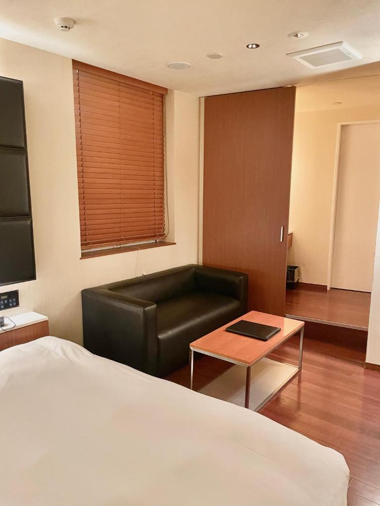 une chambre d'hôtel avec un lit, un canapé et une table dans l'établissement Hotel BIX チェックイン23時 変更不可, à Tokyo
