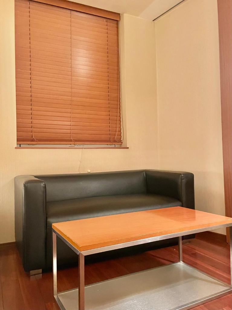 - un canapé dans une chambre avec une table et une fenêtre dans l'établissement Hotel BIX チェックイン23時 変更不可, à Tokyo