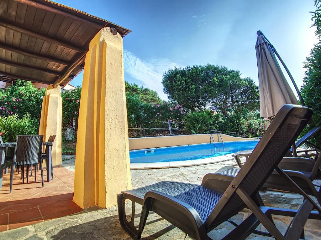 une terrasse avec une chaise, un parasol et une piscine dans l'établissement Villa Verde splendida villa con piscina - Stintino Sardegna, à Cuile Pazzoni