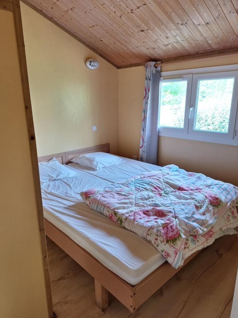 un lit dans une petite pièce avec une fenêtre dans l'établissement Camping des Papillons, à Lalizolle 37 autres photos