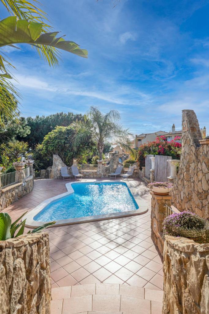 - une piscine dans une cour dotée d'un mur en pierre dans l'établissement Villa Lolly, à Quartu SantʼElena