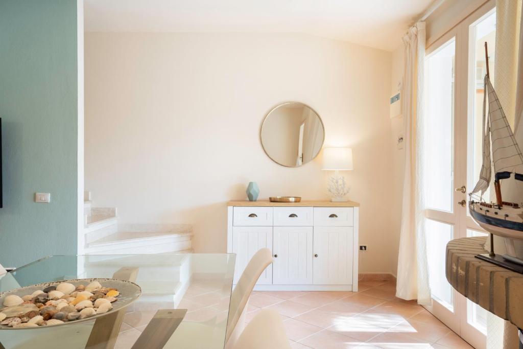 une salle à manger avec une table en verre et un miroir dans l'établissement Villa Lolly, à Quartu SantʼElena