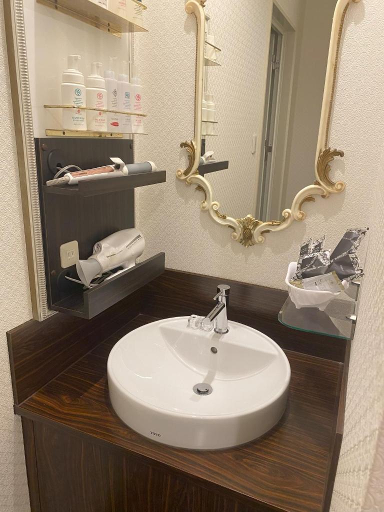 une salle de bain avec un lavabo blanc et un miroir dans l'établissement Carnet (Adult Only), à Amagasaki