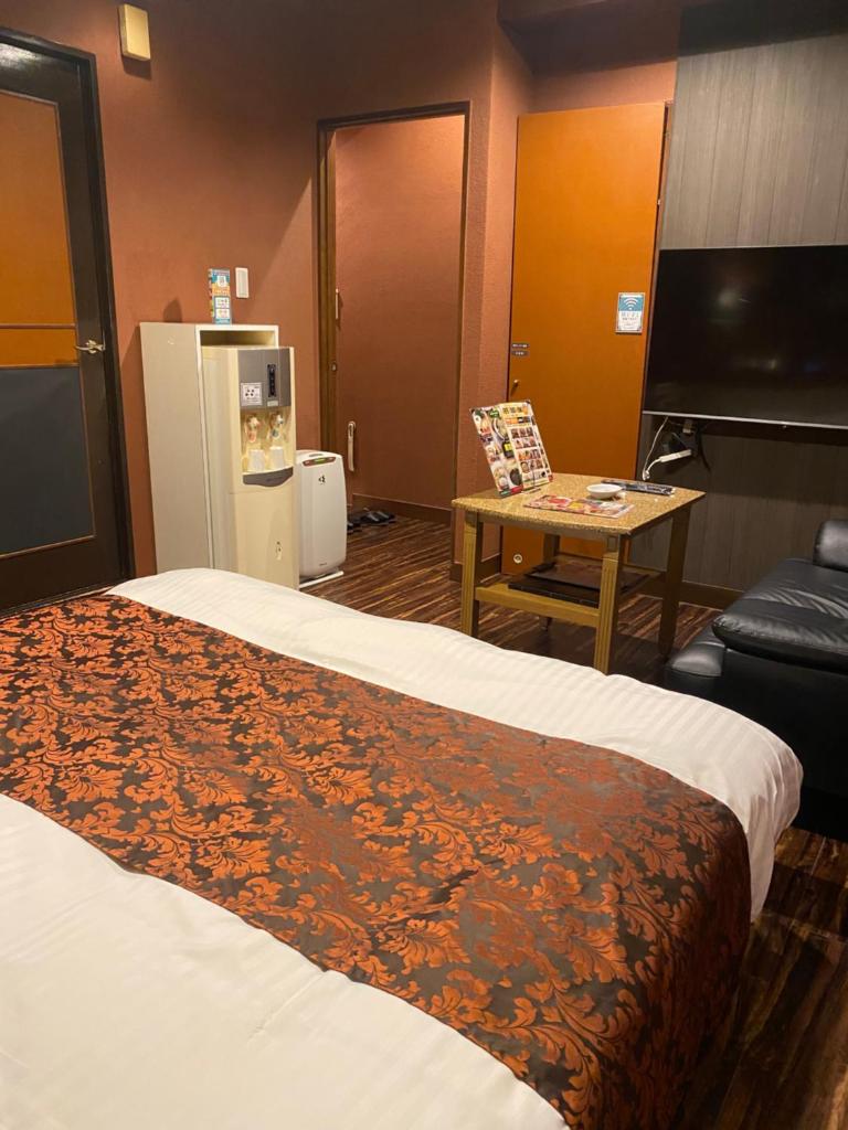 une chambre d'hôtel avec un lit, une table et une télévision dans l'établissement Carnet (Adult Only), à Amagasaki