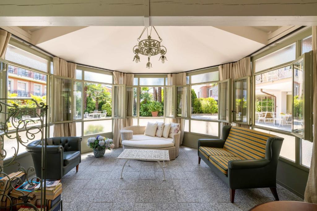 un salon avec un canapé, des chaises et des fenêtres dans l'établissement Residence Ortensia, à Baveno