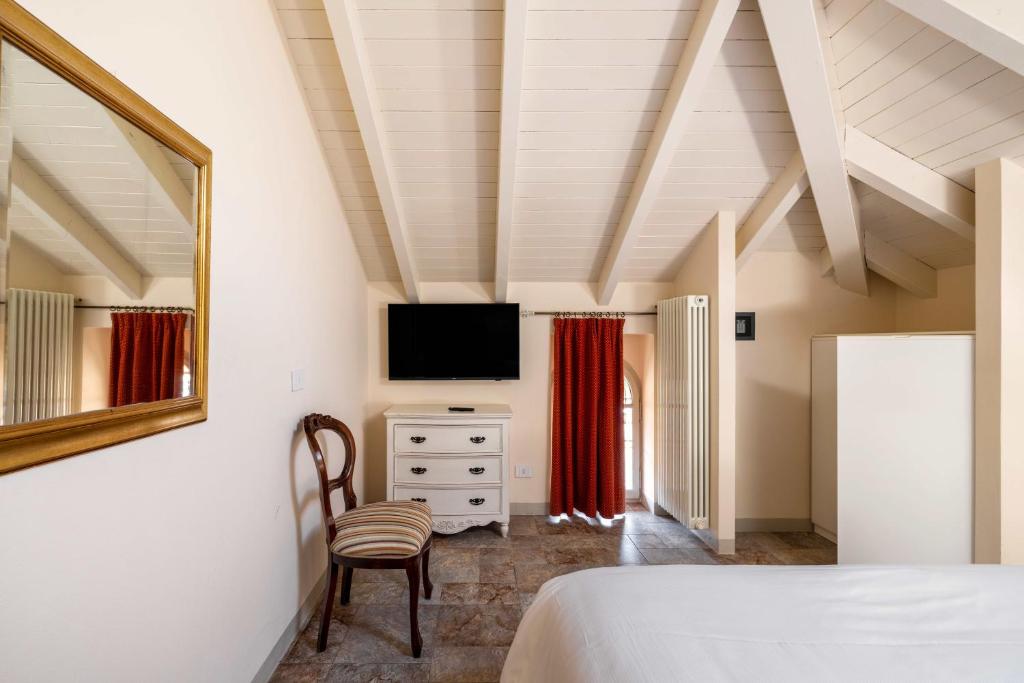 une chambre avec un lit, une télévision et une chaise dans l'établissement Residence Ortensia, à Baveno