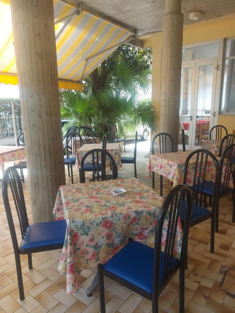 un restaurant avec des tables et des chaises et un palmier dans l'établissement Hotel Holiday Garnì - Pet Friendly, à Giulianova