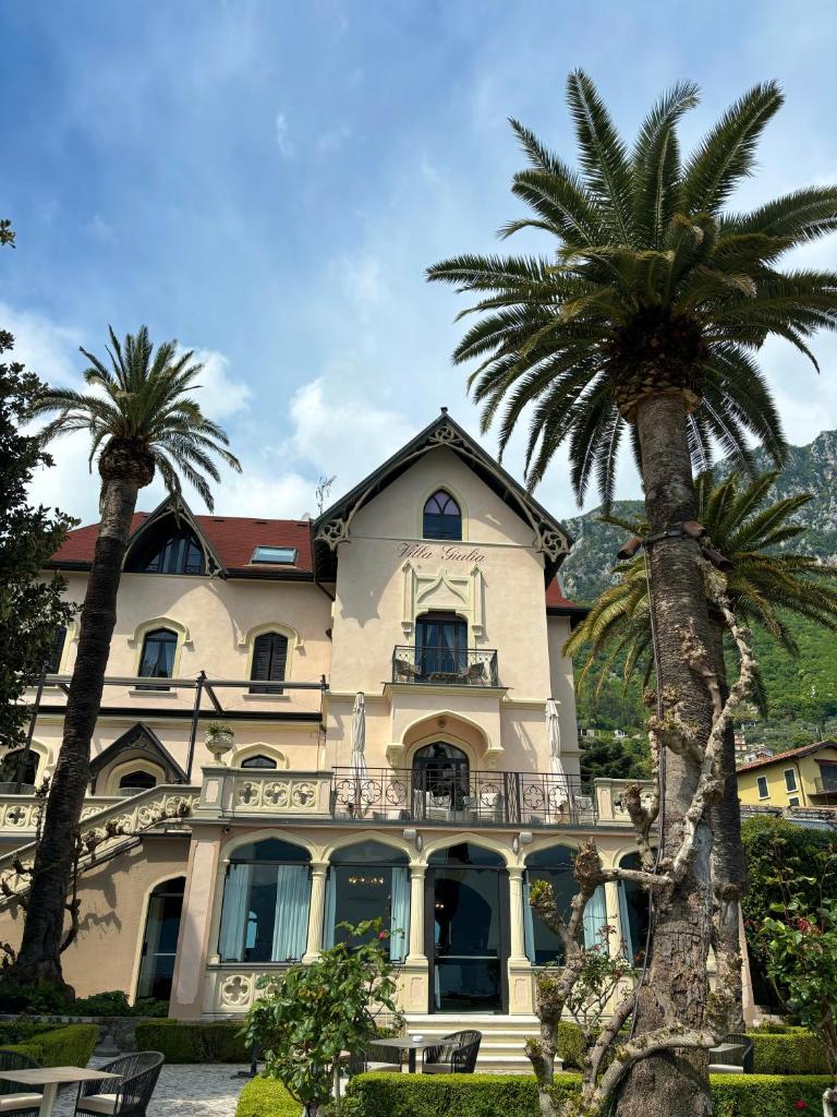 une grande maison avec des palmiers devant dans l'établissement Hotel Villa Giulia, à Gargnano