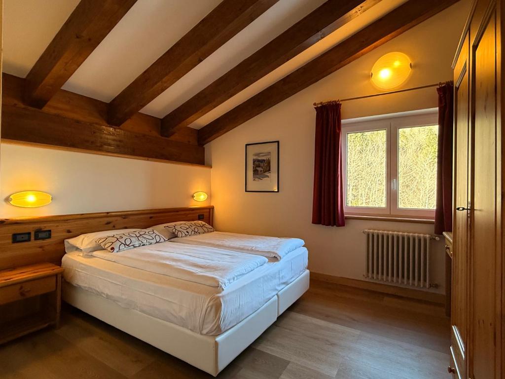 une chambre avec un grand lit et une fenêtre dans l'établissement Hotel Al Lago, à Lavarone 25 autres photos