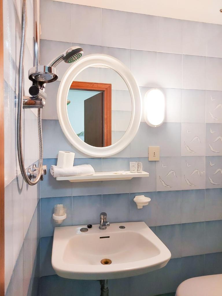 une salle de bain avec un lavabo et un miroir dans l'établissement Hotel Umberto, à Lido di Jesolo