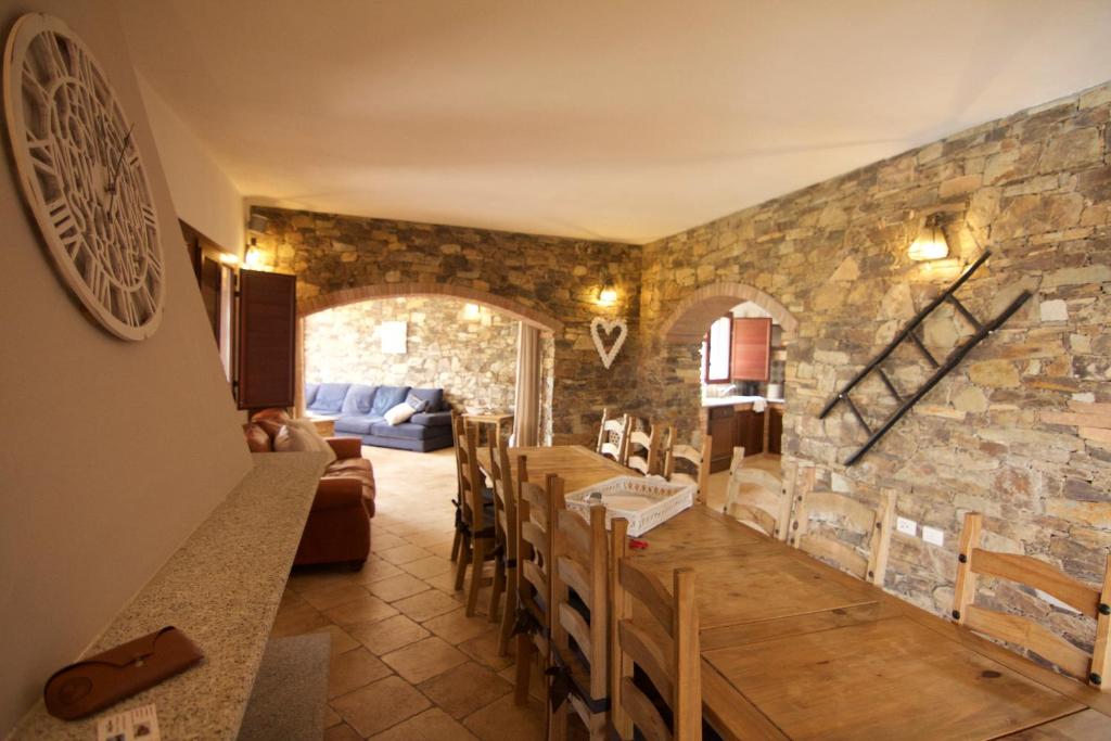 - un salon avec un mur en pierre, une table et des chaises dans l'établissement La Mariachiara, à Tertenìa