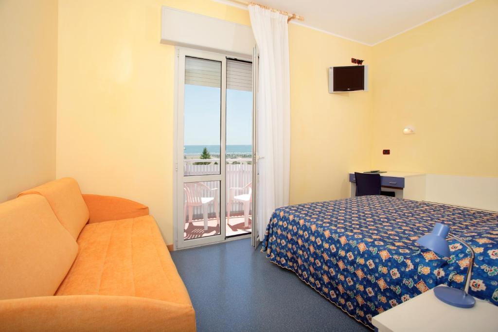 une chambre d'hôtel avec un lit, un canapé et un balcon dans l'établissement Hotel Villa Maria, à Caorle