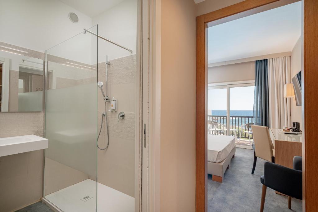 une salle de bain avec une douche avec une porte vitrée dans l'établissement Hotel Calabona, à Alghero