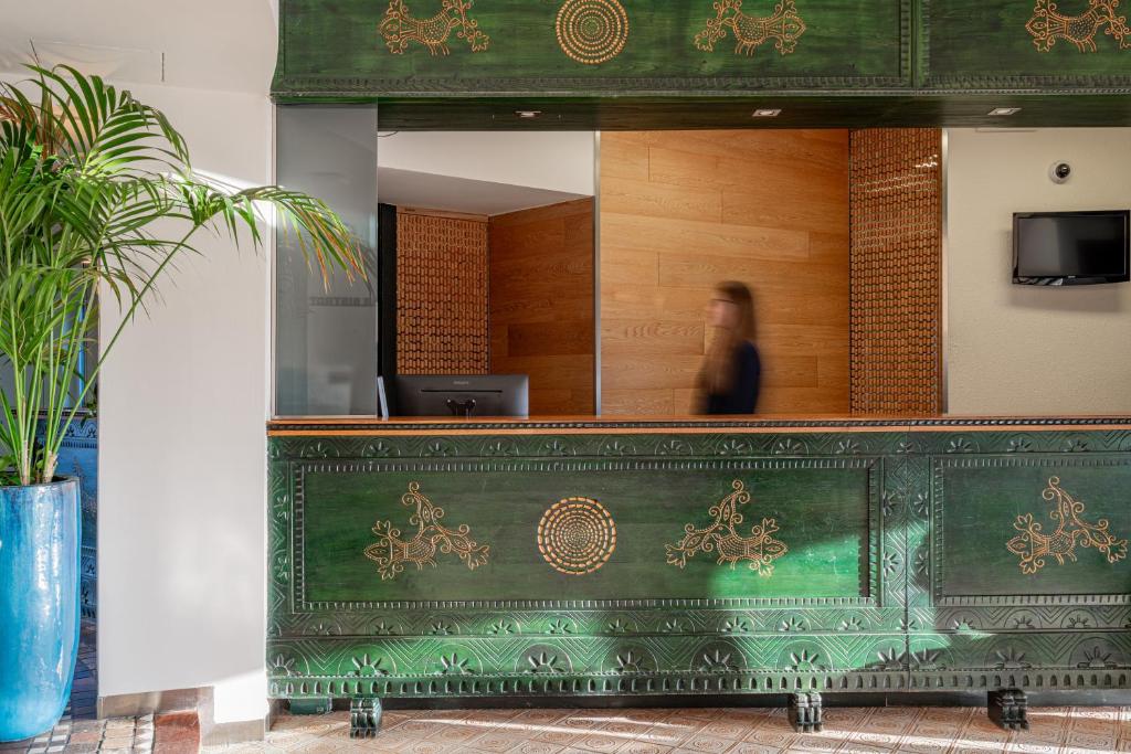 une femme se tient derrière un comptoir vert dans l'établissement Hotel Calabona, à Alghero 150 autres photos