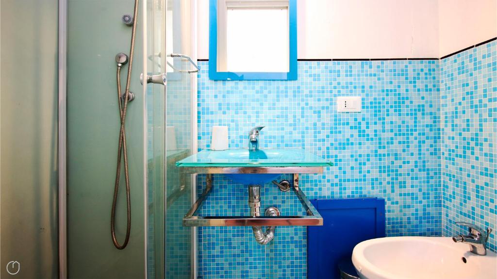 une salle de bain carrelée bleue avec un lavabo et une douche dans l'établissement Visitsicilia Villa Cialoma, à Scopello