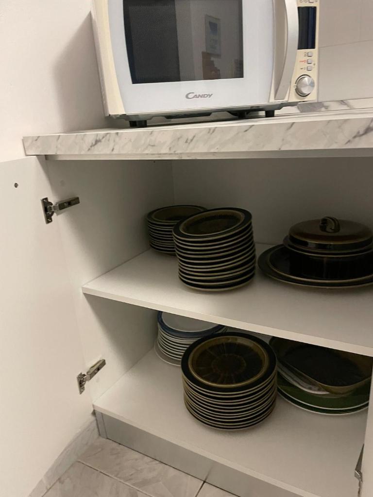 un four micro-ondes installé au-dessus d'une étagère avec des assiettes dans l'établissement Villa la Dimora di Zoè, à Ischia