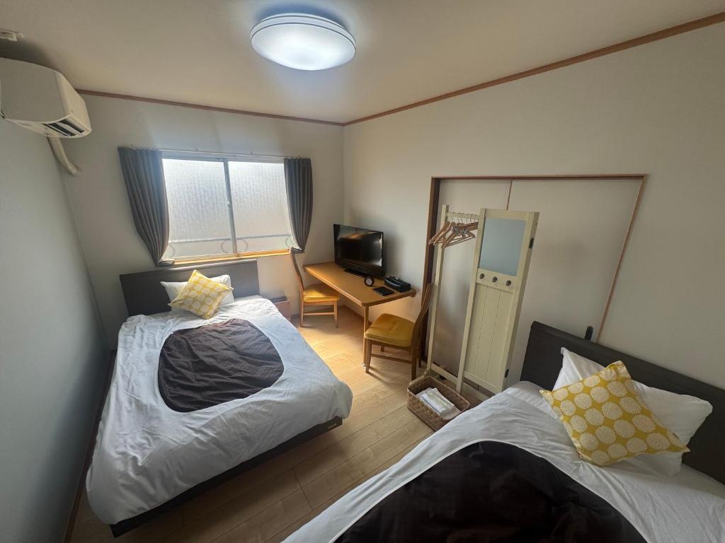 Cette petite chambre comprend deux lits et un bureau. dans l'établissement 別府 鉄輪温泉 萬力屋別館 ManrikiyaBekkan Beppu Kannawa, à Beppu