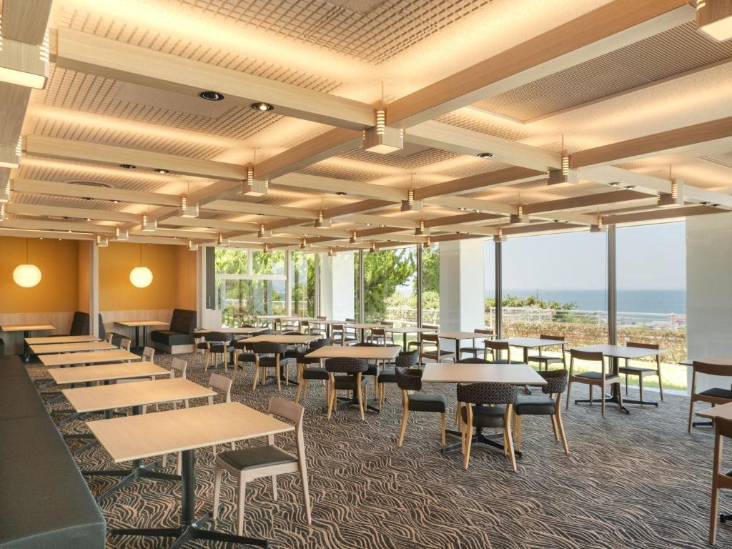 une salle à manger avec tables, chaises et fenêtres dans l'établissement KAMENOI HOTEL Awajishima, à Awaji