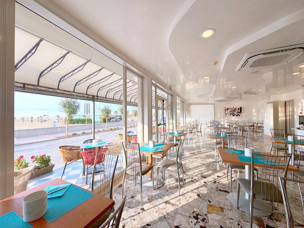 - un restaurant avec des tables et des chaises et une vue sur la rue dans l'établissement Hotel Riviera, à Caorle