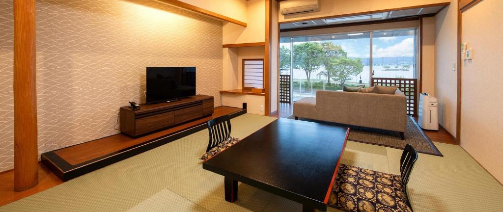 un salon avec une table à manger et une télévision dans l'établissement Hotel Saginoyu, à Suwa