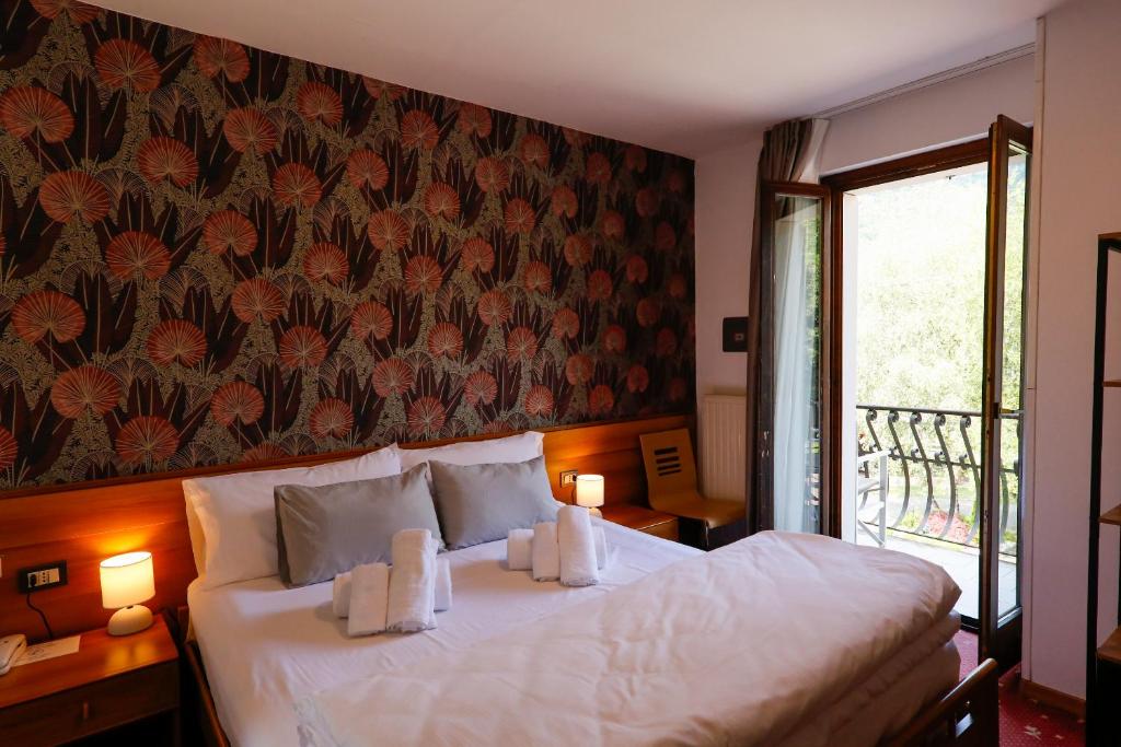 - une chambre avec un lit orné d'un mur fleuri dans l'établissement Hotel Lido, à Ledro