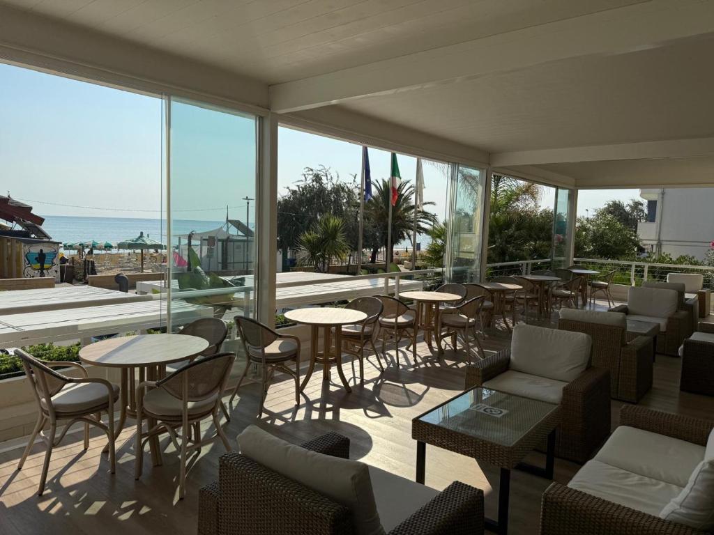 un restaurant avec des tables, des chaises et des fenêtres dans l'établissement Hotel Costa Verde, à Pineto
