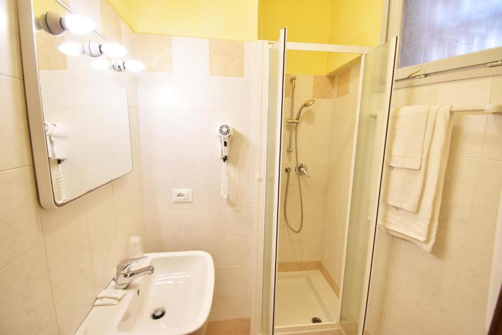une salle de bain blanche avec une douche et un lavabo dans l'établissement Hotel Galles, à Lido di Jesolo