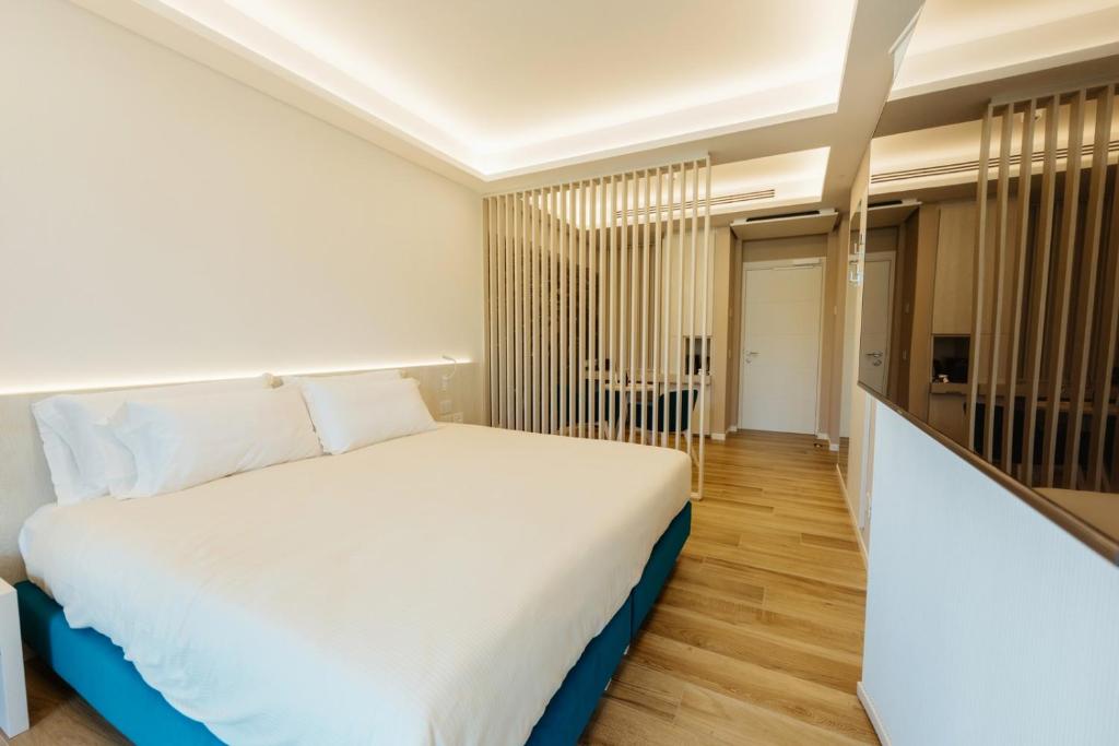 une chambre avec un grand lit blanc et du parquet dans l'établissement Wine Hotel Lugana Parco al Lago, à Sirmione 13 autres photos