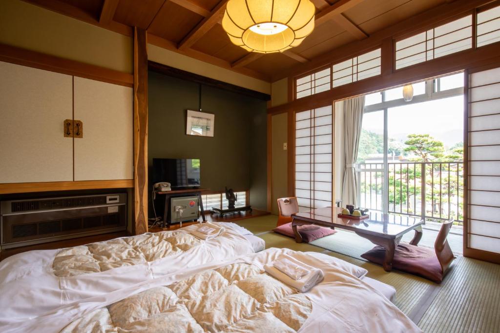 une chambre avec un grand lit et une grande fenêtre dans l'établissement Shimaya, à Yamanouchi