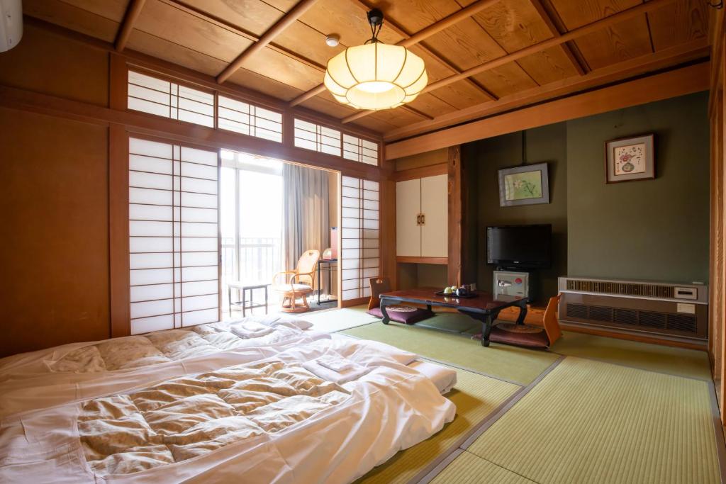 une chambre avec un grand lit et une grande fenêtre dans l'établissement Shimaya, à Yamanouchi