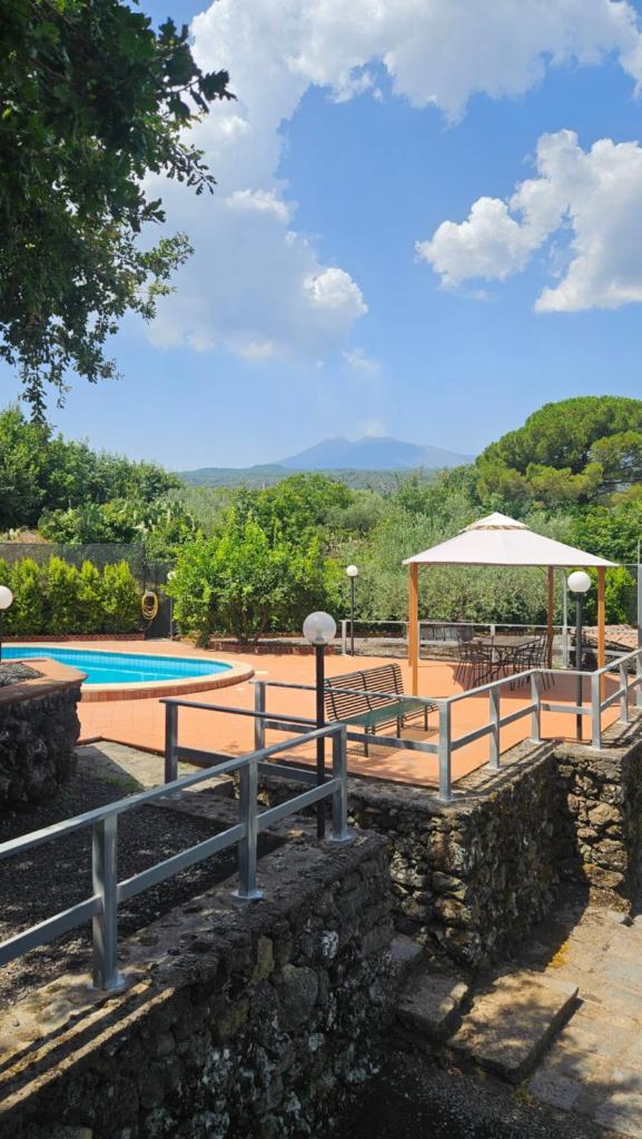 une piscine avec une table, des chaises et un parasol dans l'établissement Villa MELANY Casa Vacanza, à Piedimonte Etneo