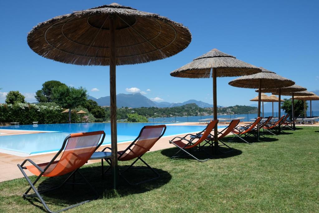 une rangée de chaises et de parasols à côté d'une piscine dans l'établissement Campeggio Villaggio San Giorgio Vacanze, à Manerba del Garda