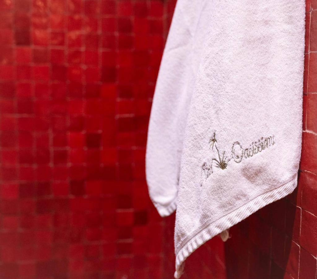 une serviette blanche accrochée à un mur avec des carreaux rouges dans l'établissement Riad Oasissime, à Marrakech