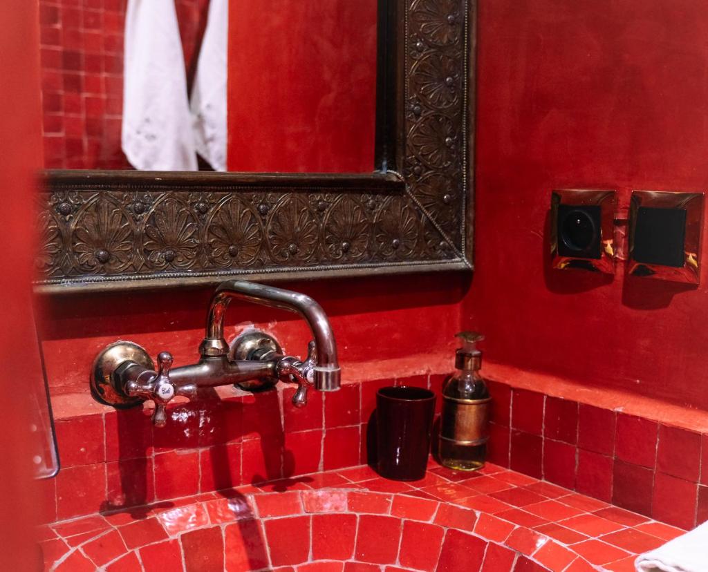 une salle de bain avec un lavabo carrelé rouge et un miroir dans l'établissement Riad Oasissime, à Marrakech