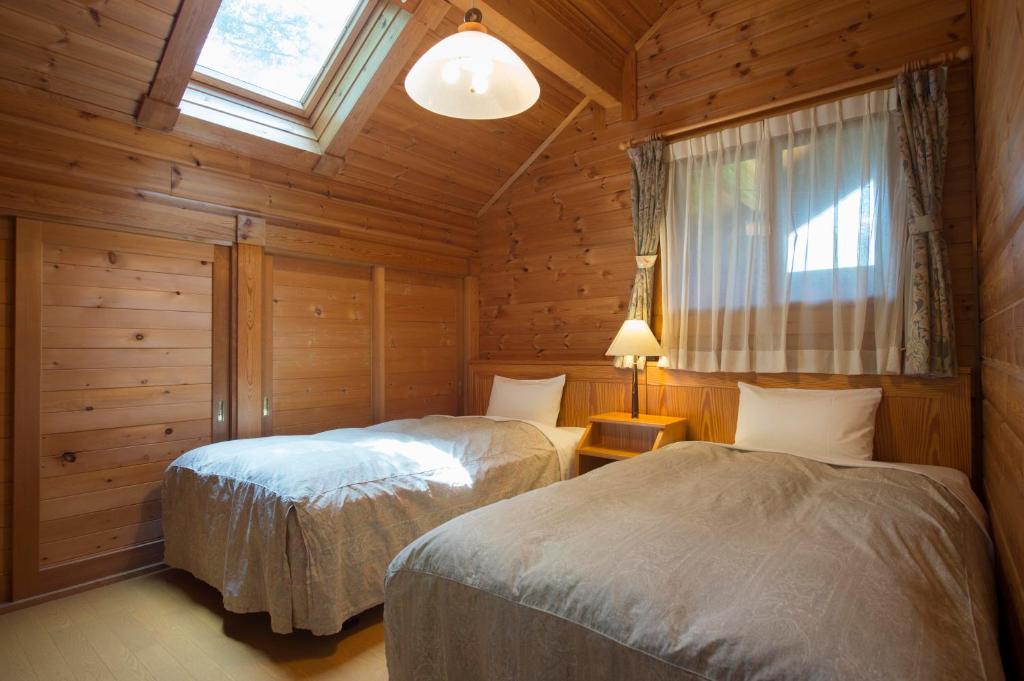 une chambre avec deux lits dans une cabane en rondins dans l'établissement Izumigo AMBIENT Azumino Cottage, à Azumino