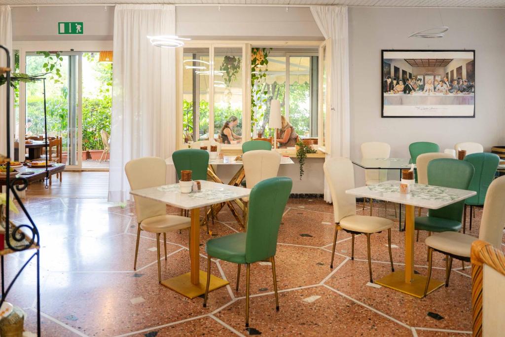 un restaurant avec des tables blanches et des chaises vertes dans l'établissement Hotel Capri, à Rimini