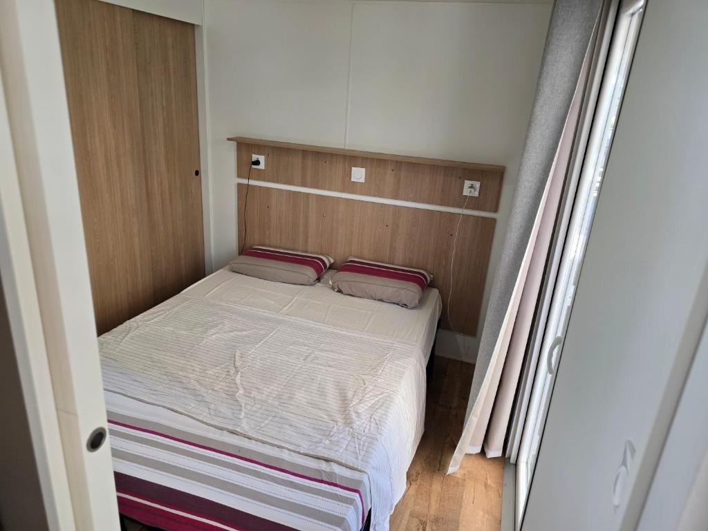 un petit lit avec deux oreillers dans une petite pièce dans l'établissement Mobil-Home La Carabasse, à Vias