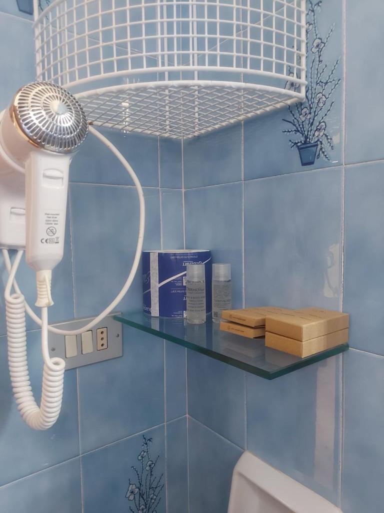 une salle de bain avec un sèche-cheveux sur une étagère dans l'établissement Hotel Holiday Garnì - Pet Friendly, à Giulianova