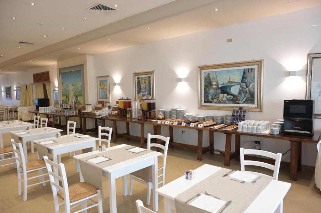 un restaurant avec des tables et des chaises blanches et un comptoir dans l'établissement Grand Hotel la Chiusa di Chietri, à Alberobello