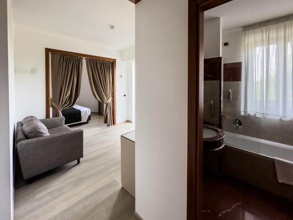 Cette chambre comprend un canapé, un lit et un miroir. dans l'établissement Grand Hotel la Chiusa di Chietri, à Alberobello