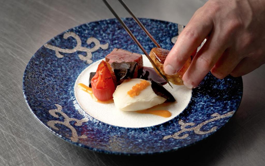 une personne mangeant de la nourriture dans une assiette bleue dans l'établissement Ogiwarakan, à Chikuma