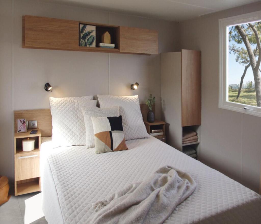 une chambre avec un grand lit blanc avec une fenêtre dans l'établissement mobil home Piriac 2 chambres 4 à 6 pers, à Piriac-sur-Mer
