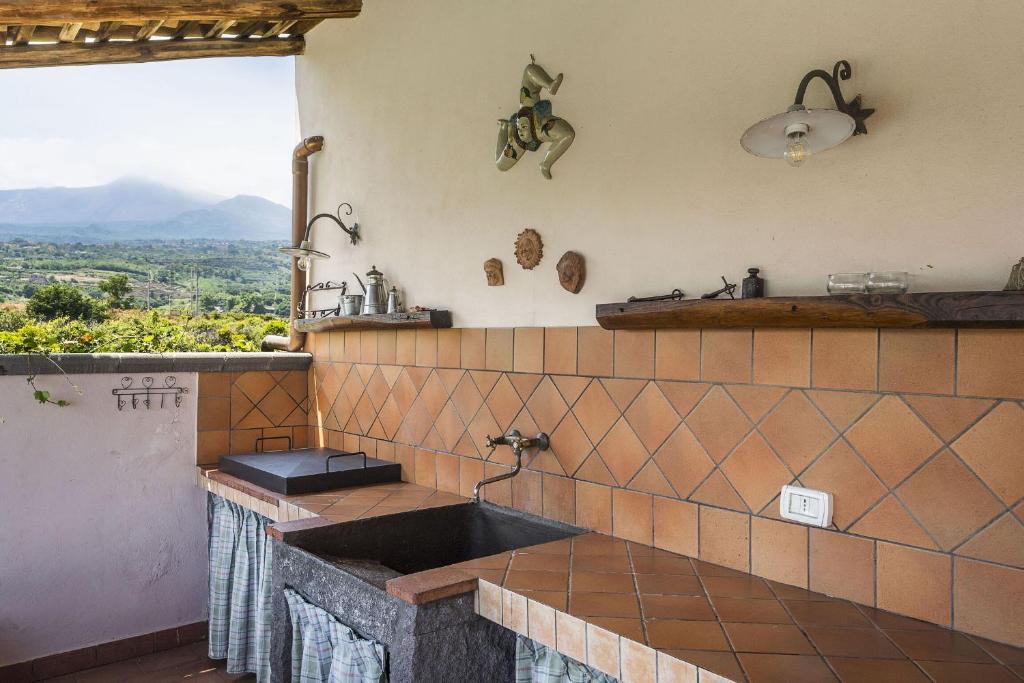 une cuisine avec un évier et une grande fenêtre dans l'établissement Villa Due Leoni, à Giarre