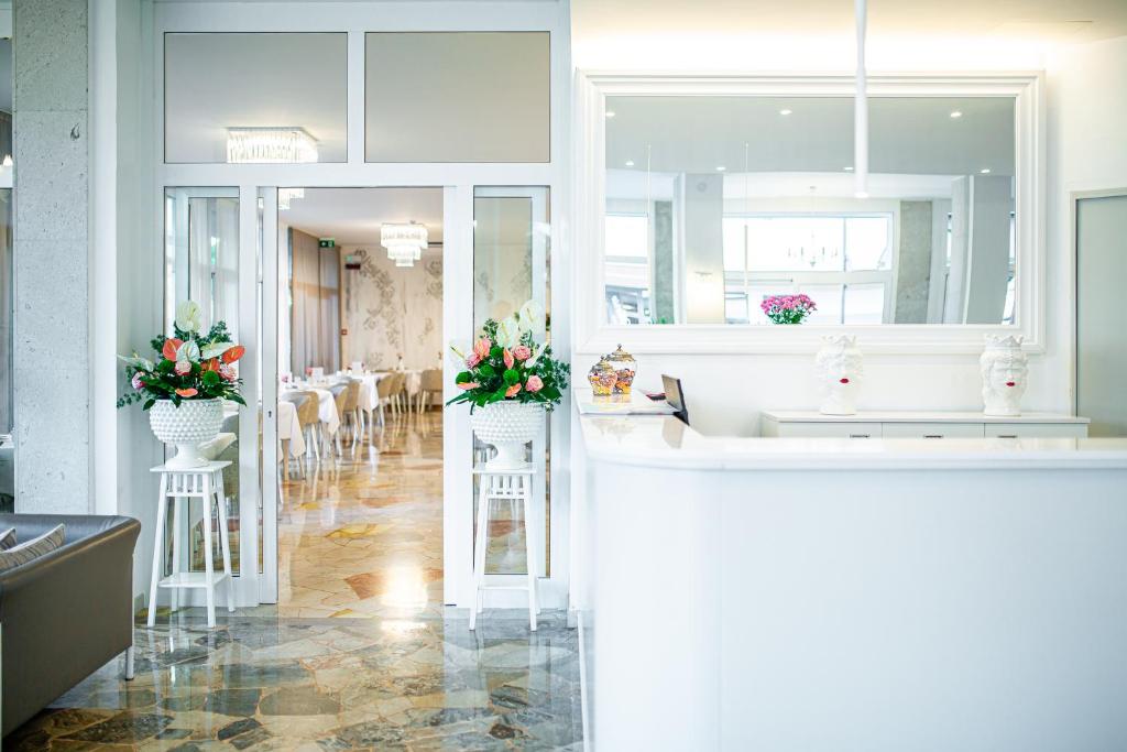 une cuisine avec deux éviers et des fleurs sur le comptoir dans l'établissement Hotel Centrale, à Lignano Sabbiadoro